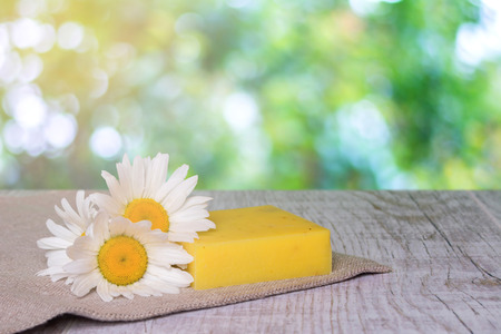 Natural handmade soap and chamomile flowers on a wooden background. A piece of soap against the background of sunlightの写真素材