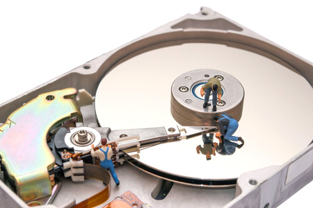 Creative concept with miniature people. Workers repairing the hard drive. A broken computer...