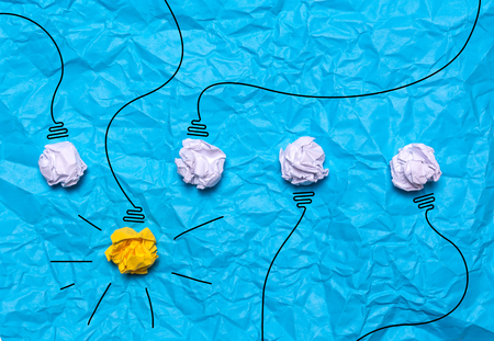Creative idea of crumpled paper. A burning light bulb on a blue background. Education conceptの写真素材
