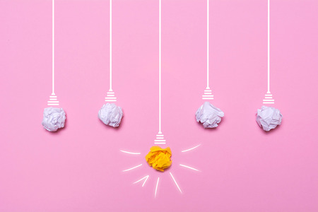 Creative idea of crumpled paper. A burning light bulb on a pink background. Education concept.の写真素材