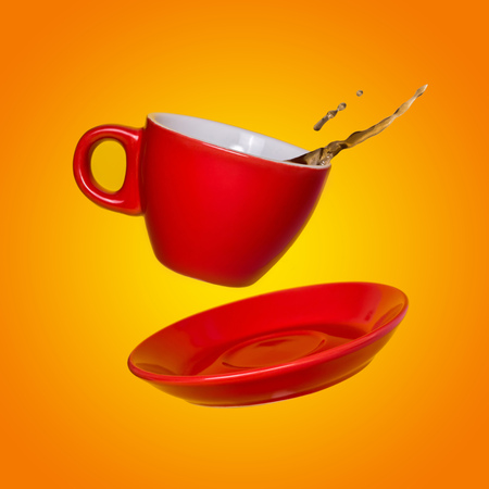Creative surreal design with a red coffee cup and saucer on a yellow background. A cup and saucer flying in the air.の写真素材