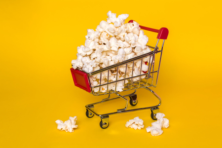 Popcorn in a shopping trolley. A bunch of popcorn on a white background. Surrealistic conceptの写真素材