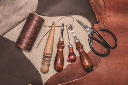 Tools for leather crafting and pieces of brown leather. Manufacture of leather goods. View from...