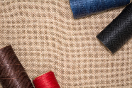 Four coils of threads on a linen background. Red, blue, brown and black threads. View from above.の写真素材