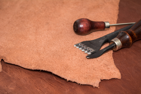 Tools for leather crafting and pieces of brown leather. Manufacture of leather goods.