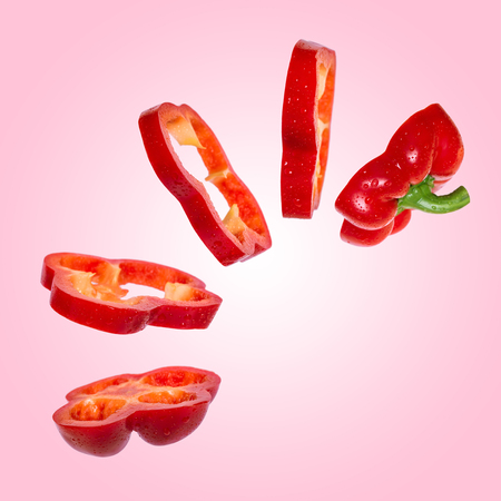 Creative concept with flying red paprika. Sliced floating pepper. Levity capsicum vegetable on pink...