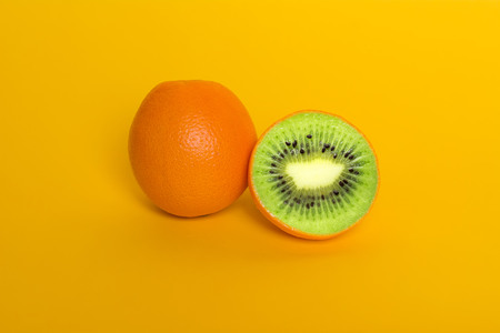 Collage orange with kiwi. Orange on yellow background. Surrealism fruits. Genetically modified food GMOの写真素材