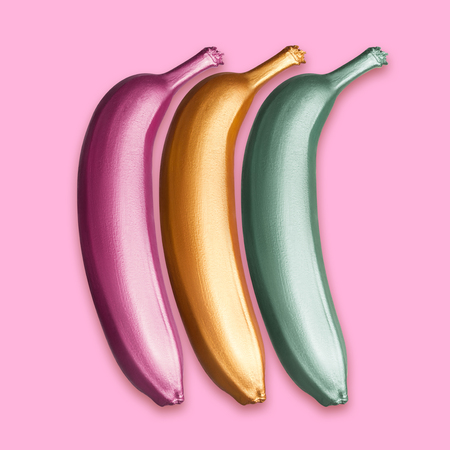 Purple, gold and green metallic golden bananas on a pink background. A modern creative concept. Contemporary artの写真素材