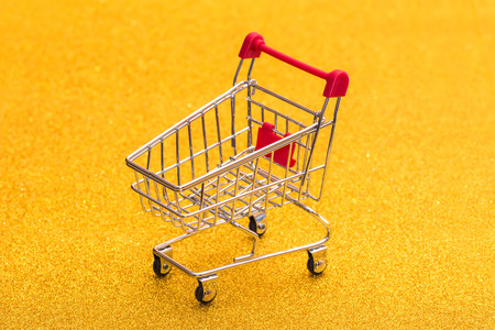 Empty shopping trolley on a golden radiant background. Shop basket for productsの写真素材