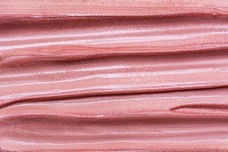 Texture of lip gloss. Smudged makeup product sample. Sparkling background.の写真素材