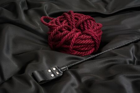 Stack for BDSM games and shibari rope on black silk background. Accessories for adult sexual gameの写真素材
