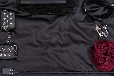 Leather handcuffs, shibari rope, nipple clamps, chain collar and stack on black background. Accessories for adult sexual game. BDSM outfit.の写真素材