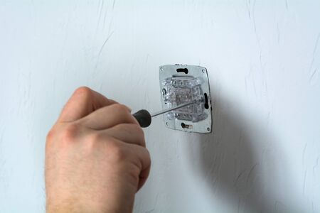 Socket plug installation. Disassembled electrical outlet in detonation wall with bare wires and...
