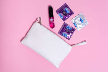 Kyiv, Ukraine - 21 May 2020: Durex condoms Elite, Invisible and Durex Intense Orgasmic gel near a white cosmetic bag on a pink background. Health and safe sex.のeditorial素材