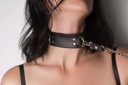 The young woman is wearing a black leather collar. Conceptual BDSM photo.の写真素材