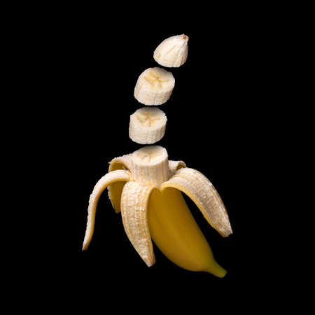 Banana isolated on black background. Surreal design. Pieces of fruit floating in the airの写真素材