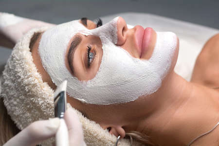 Applying a mask to the face in a beauty salon. Cosmetologist and procedure for rejuvenation and...