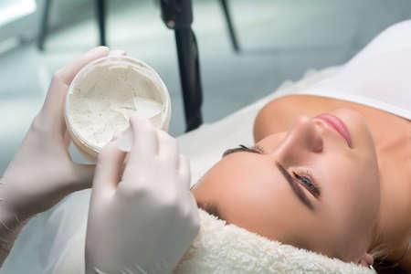 Applying a mask to the face in a beauty salon. Cosmetologist and procedure for rejuvenation and moisturizingの写真素材
