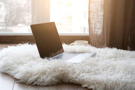 Work from home. Cozy workplace near the window for remote work and business online. Coffee table with a laptop. Quarantine, coronavirus concept.