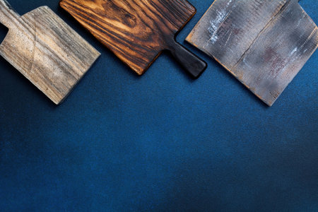 Set of old stylish wooden cutting board on a blue background. Kitchenware top view. Empty space for your ready mealsの写真素材