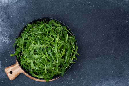 Fresh arugula on a black plate. Handful of fresh lettuce, healthy eating, superfood. View from above, flat lay.の写真素材