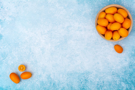 Kumquat in a wooden bowl on a blue background.の写真素材