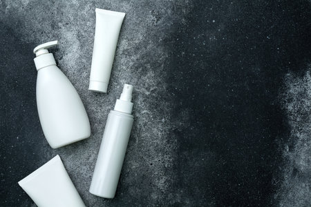 Set of white empty cosmetic bottles on black background. Top view with copy spaceの写真素材