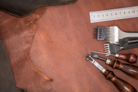 Pieces of natural calf leather and tools for leather processing. A leather craftsman's workshop.の写真素材