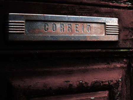 Old and rusty mail slot in an equally old door. The portuguese word の写真素材