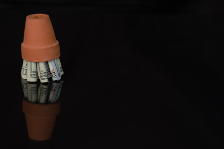 Money in terracotta pot with reflectionの写真素材
