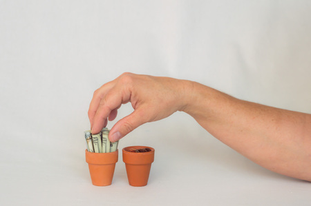 Hand putting money in terracotta potの写真素材