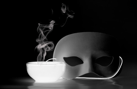 Glowing bowl and mask on a black background with smoke risingの写真素材