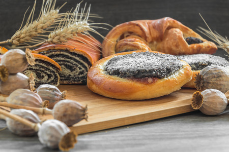 somepoppy seed cake and strudel on a wooden board, poppys' heads in the foregroundの写真素材