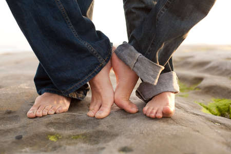 a couples feet touch on the beach
