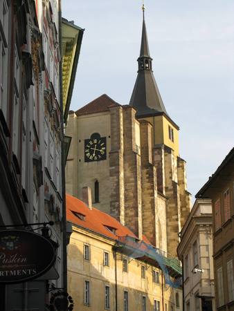 Historical monument - an old church with a pointed tower and clock at the end of a narrow alleyの写真素材