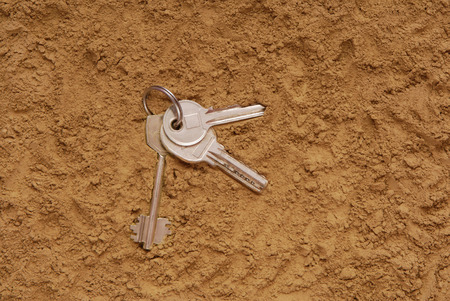 lost keys are on the sand, find keys are on the ground, key are as a clue, metal keys are on the texturing backgroundsの写真素材