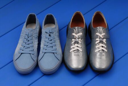 leather blue footwear, shine sneakers, grey trainers are on blue wooden background, fashionable boots are on show-window, sports shoes are in the window, contemporary  art installation, color combinations, beautifil colours, silver-colored bright color, aristic photography の写真素材