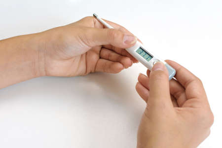 Woman hands holding white digital medical thermometer with high temperature. Healthcare concept