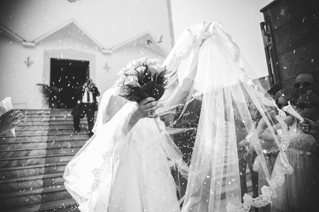 Bride covering herself from the rice, with the veilの写真素材