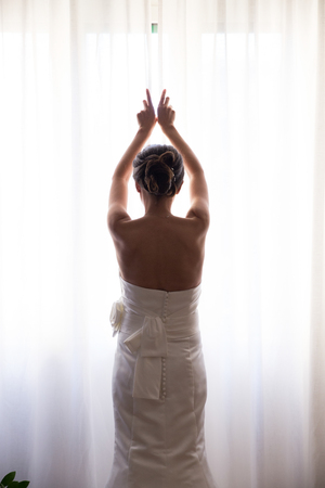 Bride opening the window curtainsの写真素材