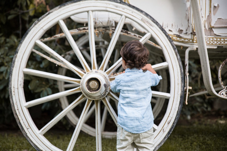 Child playing with a wheel of an old carriageの写真素材