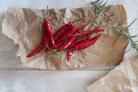red chili peppers on a brown paper and a sprig of fresh rosemary top viewの写真素材