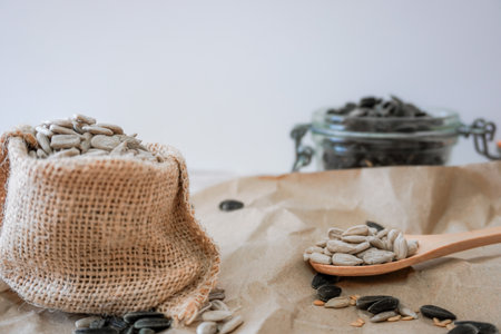 bag with sunflower seeds and wooden spoon brown background with white copy space