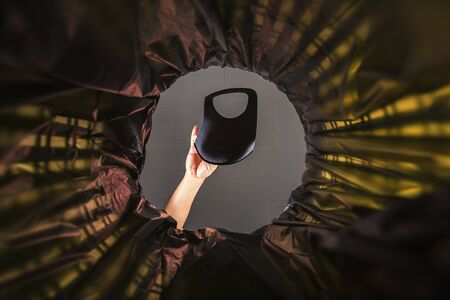 Throwing a face mask into the trash. With a worm view from the inside of the trash bin.の写真素材