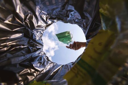 Face mask pack in zip lock before throw into the trash. With a worm view from the inside of the trash bin.の写真素材