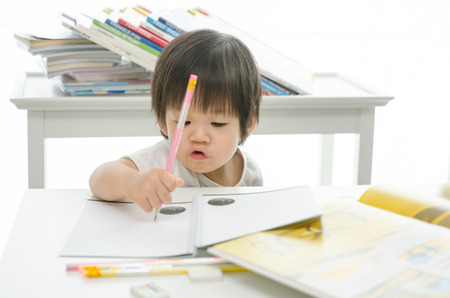 Little asian boy is writing on a book の写真素材