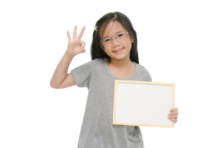 Little Asian girl holding empty whiteboard on white background