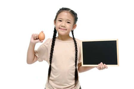 Little asian girl holding egg and black boardの写真素材