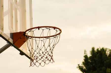 Close up of a basketball hoop, under the sunset.