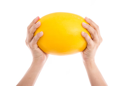 Female's hand holding honeydew melon on a white background isolatedの写真素材